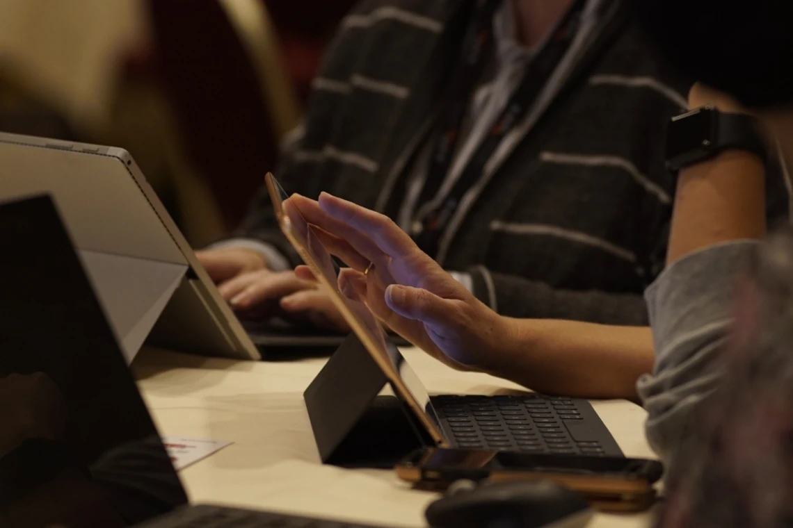 a school librarian uses a tablet while sitting at a table
