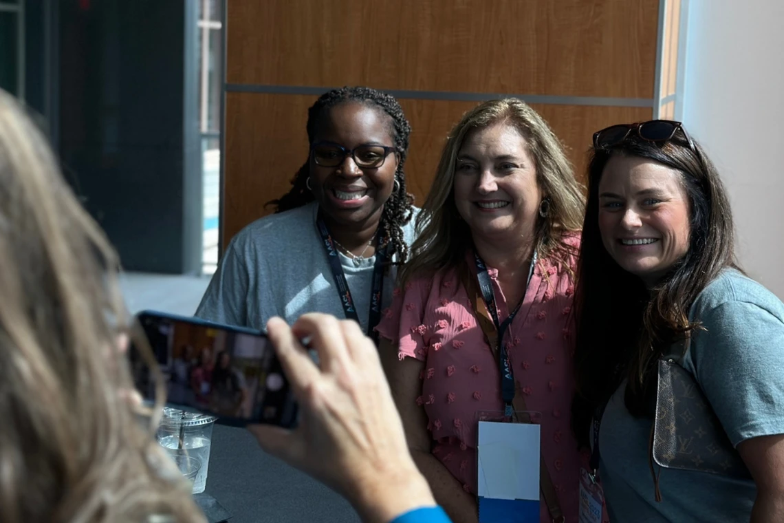 three school librarians pose while a four takes their picture with a smart phone